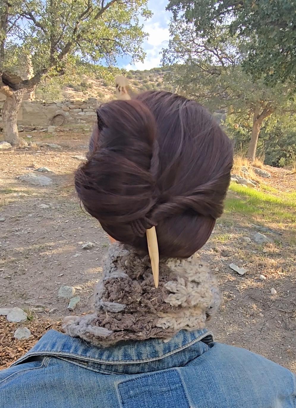 Single-tine cottonwood hair fork in a half-up bun on long hair — lightweight wooden hair accessory.