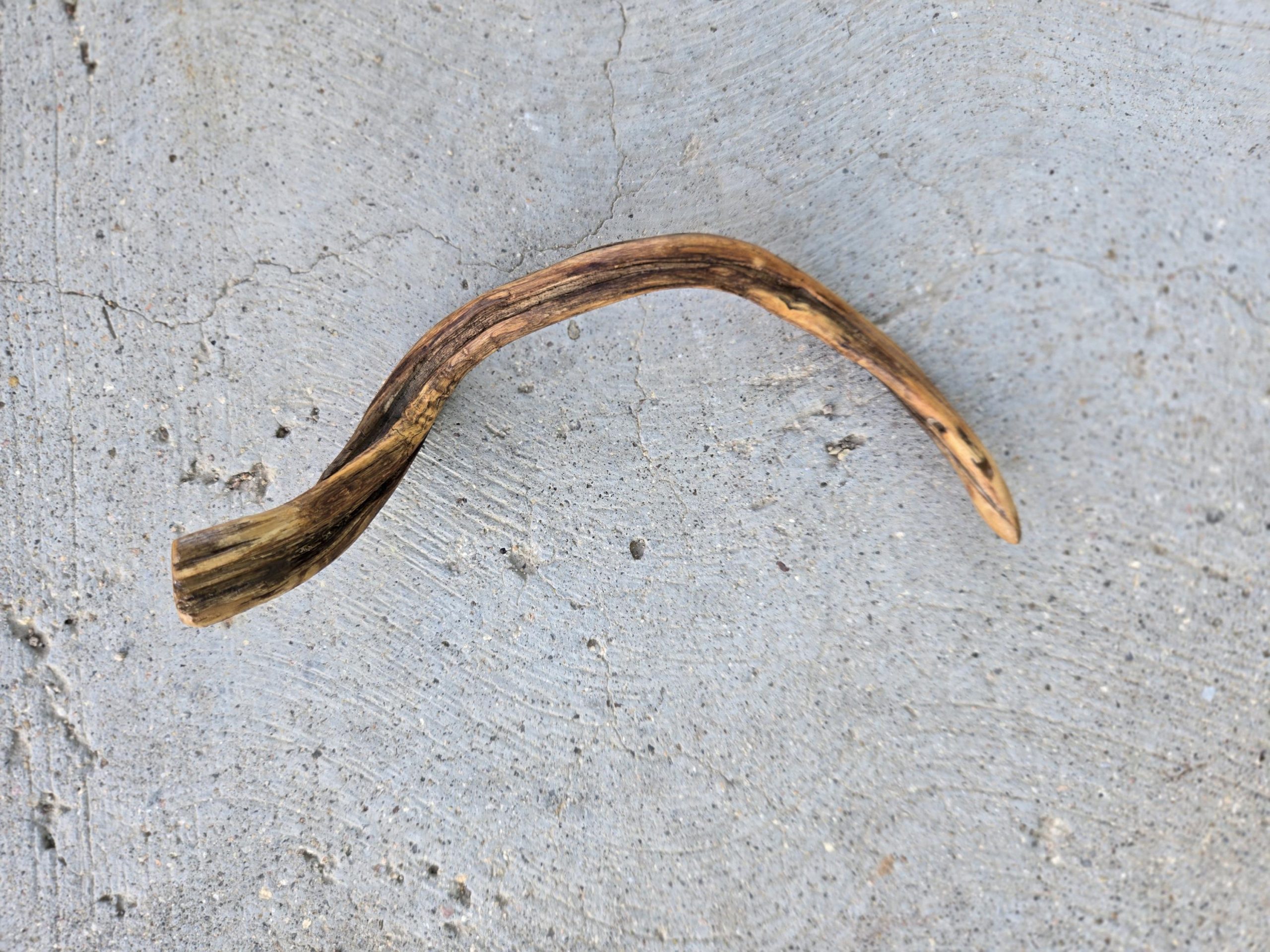 Close-up of twisted wood grain on a handcrafted single-tine hair fork — natural materials, handmade craft.